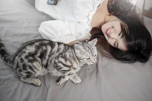 hermosa mujer asiática amante de los gatos está jugando con un gato en su habitación foto
