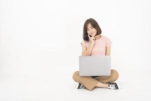 Una linda adolescente asiática está trabajando con una computadora de fondo blanco