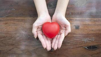 la mano de la mujer sostiene el corazón rojo, el amor y el concepto de atención médica foto