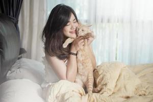 hermosa mujer asiática amante de los gatos está jugando con un gato en su habitación foto