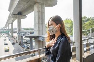 hermosa mujer con máscara antipolvo protege la contaminación del aire y pm 2.5 en la ciudad de la calle foto