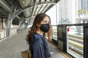 hermosa mujer con máscara antipolvo protege la contaminación del aire y pm 2.5 en la ciudad de la calle foto