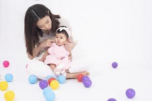 la madre asiática y la adorable niña son felices con antecedentes blancos foto