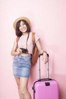 Happy Asian woman tourist  on pink background photo