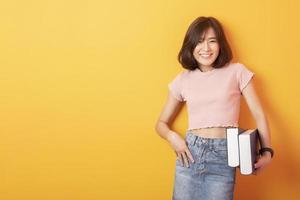 bella estudiante universitaria asiática feliz con antecedentes amarillos foto
