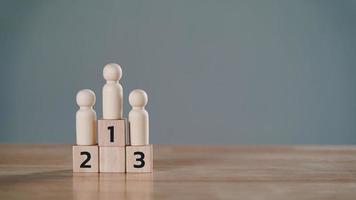 wooden figures peg doll standing on the podium 1st, 2nd, 3rd positions of wooden cube blocks with copy space. ranking and strategy concept. photo