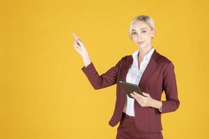 Business woman is pointing something on yellow  background photo