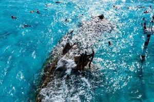 People snorkelling around the ship wreck near Cancun in the Caribbean sea.