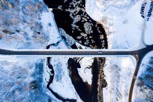 Curvy windy road in snow covered forest, top down aerial view. photo