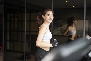 Beautiful asian sport woman is running on treadmill in the gym
