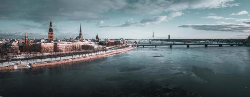 hermosa vista del río congelado con gaviotas sentadas en el hielo junto al casco antiguo de riga en letonia. foto