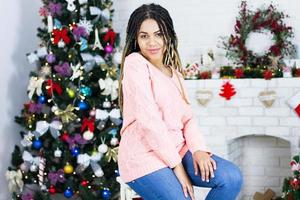 retrato de hermosa mujer negra en luces. moda y maquillaje. Papá Noel de Navidad. dama elegante en vestido rojo sobre fondo de luces de árbol de Navidad. Feliz año nuevo. foto