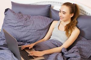Smile woman browsing internet in a laptop in the bedroom at home photo