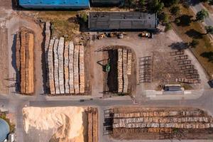 Muro de pilas de madera fuera de la fábrica con un patio industrial foto