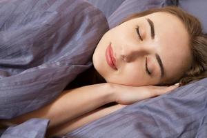retrato hermosa mujer joven durmiendo mientras está acostado en su cama. concepto de reincorporación placentera y de descanso para la vida activa foto