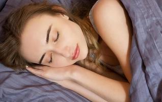 Portrait of Beautiful young woman sleeping while lying in bed comfortably and blissfully - sun shines from the window on her face photo