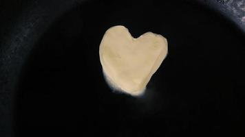 boter in de vorm van een hart dat smelt op hete pan - close-up bovenaanzicht video