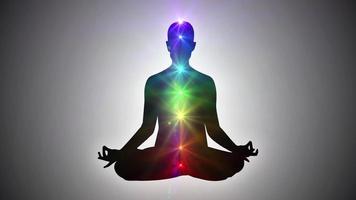 Silhouette einer Person, die in Lotus-Yoga-Pose sitzt und Nirvana oder Erleuchtung erreicht - sieben Chakren video