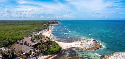 costa aérea de tulum junto a la playa con un mágico mar caribeño y pequeñas cabañas junto a la costa. foto