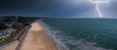 Flying over cloudy stormy beach in Bournemouth, England.