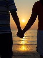 Silhouettes couples holding hands on sunset. photo