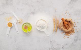 The ingredients for homemade pizza dough with wheat ears ,wheat flour and olive oil set up on white concrete background. top view and copy space. photo