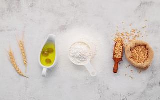 The ingredients for homemade pizza dough with wheat ears ,wheat flour and olive oil set up on white concrete background. top view and copy space. photo