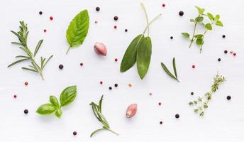 Various of spices and herbs on wooden background. Flat lay spices ingredients rosemary, thyme, oregano, sage leaves and sweet basil on white wooden. photo