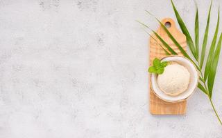 sabores de helado de coco en la mitad de la instalación de coco sobre fondo de piedra blanca. concepto de menú de verano y dulce. foto