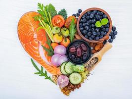 forma cardíaca del concepto de dieta cetogénica baja en carbohidratos. ingredientes para la selección de alimentos saludables sobre fondo blanco de madera. foto