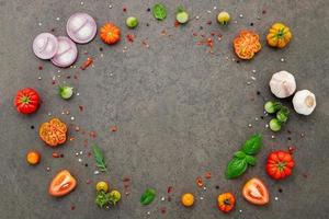 The ingredients for homemade pizza set up on dark stone background. photo