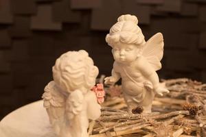 two statues of angels with wings and a wreath of twigs on a dark background for Christmas photo