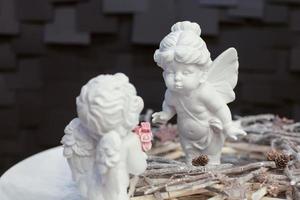 two statues of angels with wings and a wreath of twigs on a dark background for Christmas photo