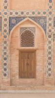 Wooden door with ancient traditional Asian ornamentation and mosaics. the details of the architecture of medieval Central Asia photo