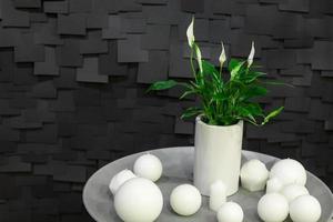 decoration of globular candle and a vase with a flower on a white plate on a dark background with tiles photo