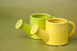 souvenir toy ceramic watering-can on a green background close up photo