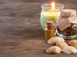 coloque ingredientes y especias para aromaterapia y cuidado corporal en una superficie de madera. llama de vela encendida. bodegón balneario foto
