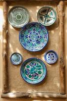 eastern ceramic plates hang on a clay wall. the wall of clay is decorated in an oriental style with a ceramic plate and wooden blocks photo