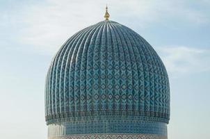 The top of the dome with tiles and mosaics in ancient Asian style. the details of the architecture of medieval Central Asia photo