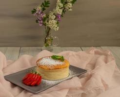 fresh cheesecake with strawberries and vase with flowers photo