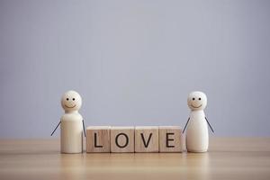 persona feliz de la familia de madera modelo una carita sonriente con la palabra amor en el fondo de la mesa de cubo de madera foto