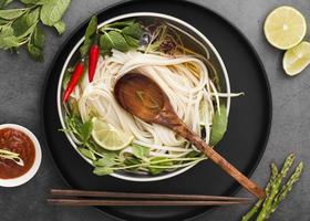 flat lay noodles bowl with spoon sauce