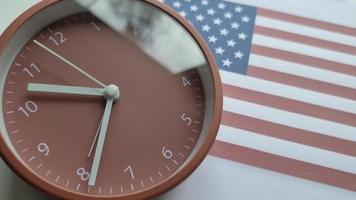 4k time-lapse du mouvement des aiguilles de l'horloge. horloge sur le fond du drapeau des États-Unis d'Amérique. video