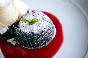 Chocolate fondant lava cake with strawberries sauce on a white plate photo