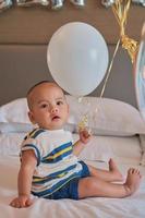 Portrait of happy 6 month old Asian baby boy sitting on bed playing photo