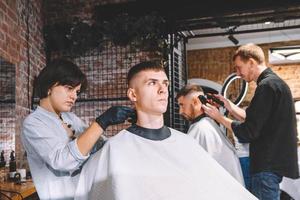 Los peluqueros cortan a sus clientes en la barbería. concepto de publicidad y peluquería. foto