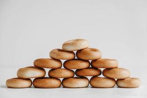 secado o mini bagels redondos en forma de pirámide sobre un fondo de madera blanca. copiar, espacio vacío para texto foto