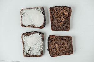 Sliced of brown bread with butter on a white wooden background photo