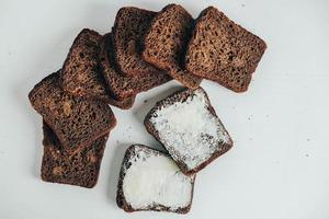 Sliced of brown bread with butter on a white wooden background. Top view. Copy, empty space for text photo