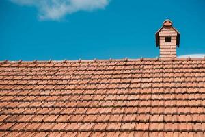 Old roof tiles on the roof of an house with chimney on sky background photo